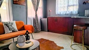 a living room with an orange couch and a table at Bavarian Maun Apartments in Maun