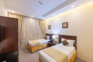 a hotel room with two beds and a television at Joury Al Mashaer Hotel in Mecca