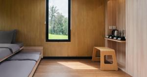 a bedroom with a bed and a window and a stool at Bobocabin Umarato, Sumba in Waikabubak