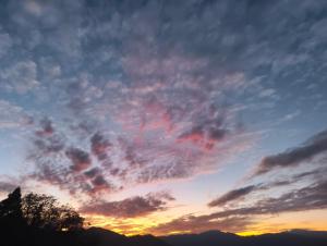a cloudy sky at sunset with mountains in the background at Tholangi Homes in Darjeeling +10 photos