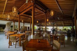 a restaurant with wooden tables and chairs in a building at Pertiwi Bisma 1 in Ubud