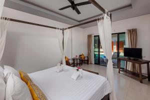 ein Schlafzimmer mit einem Bett mit weißen Laken und einem Fernseher in der Unterkunft Phuketa Hotel Phuket Town in Phuket