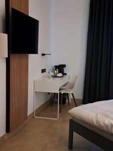 a white desk with a chair and a television in a room at Augenblick Goodnight in Kleve