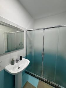 a bathroom with a sink and a glass shower at Cloud 4 Apartment in Lezhë +8 photos