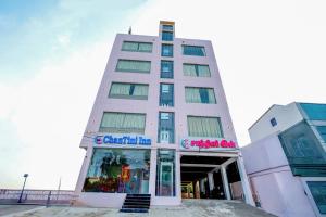 a tall white building with a sign on it at ChanTini Inn in Velankanni
