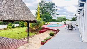 a patio with a thatch roof and a swimming pool at Rio Lodge in Butterworth