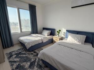 a bedroom with two beds and a large window at Beautiful Salalah Beach Apartments - 1 by Beautiful Salalah Tours in Salalah