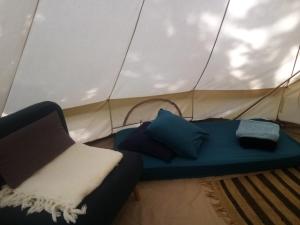 a couch in a tent with pillows on it at Tente Tipi en plein cœur d'une forêt in Burzet