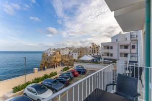ein Balkon mit einer Reihe von Autos, die neben dem Meer geparkt sind in der Unterkunft Malù Bed&Breakfast in Polignano a Mare