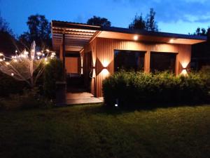 a small wooden house with lights on it at night at Tīkli 3 in Bigauņciems +3 photos