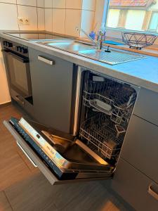 an open dishwasher in a kitchen with a sink at Freudenstadt City Apartment in Freudenstadt +18 photos
