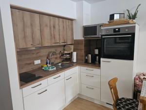 a kitchen with white cabinets and a sink and a microwave at Allgäuschönheit inkl BadHindelangPlus Karte in Bad Hindelang