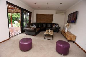 a living room with a leather couch and purple stools at African Oasis Morrocco in Somerset West