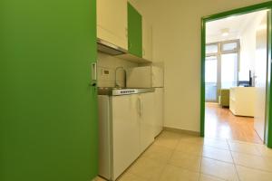 a kitchen with white appliances and a green wall at SC Pula Rooms & Studio in Pula