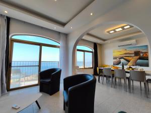 a dining room with a table and chairs and windows at Seafront 3 bed Panoramic SeaViews Apt B7- in Qbajjar