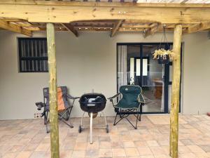 a patio with two chairs and a grill at Cosy cottage on Cassia in Gqeberha