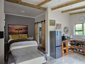 a bedroom with a bed and a refrigerator at Cosy cottage on Cassia in Gqeberha