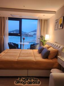 a bedroom with a large bed with a large window at 히얼마리나 in Ungch'ŏn-ni