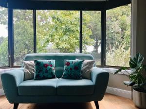 a blue couch in front of a large window at Casa Lonita - Indoor Pool & Spa in Beechworth