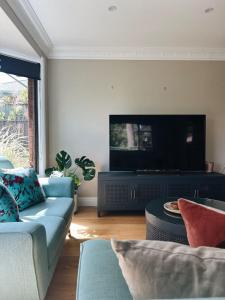 a living room with a couch and a flat screen tv at Casa Lonita - Indoor Pool & Spa in Beechworth