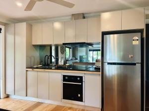 a kitchen with white cabinets and a stainless steel refrigerator at Casa Lonita - Indoor Pool & Spa in Beechworth +16 photos