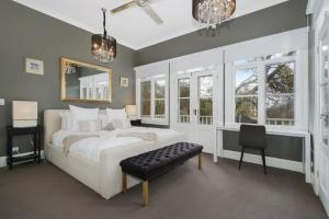 a bedroom with a bed and a chair and windows at Malakoff House - Charm & Luxury in Beechworth +17 photos