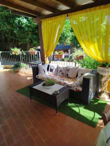 a couch on a patio with a table and yellow curtains at Gatto Matto in Manziana