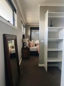 a room with a mirror and a bedroom with two beds at The Sunset Deck in Beechworth