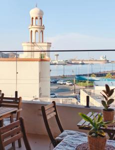 a balcony with a table and chairs and a lighthouse at Bait mutirah guesthouse in Muscat