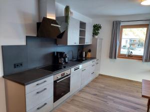 a kitchen with white cabinets and a black counter top at Apart s'Peintl in Obertilliach