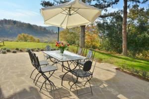 a table and chairs with an umbrella on a patio at Villa Cielo- Cignella Resort Tuscany Accommodation in Osteria Delle Noci