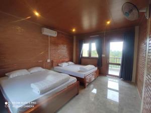 a bedroom with two beds and a balcony at Cat Tien Riverside Lodge in Tân Phú