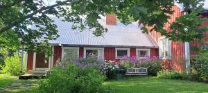 a red house with a bench and flowers in the yard at Rantakorpi Farm in Niemisjärvi +4 photos