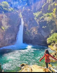 a woman standing on a rock near a waterfall at Refugio Ruta Río Borosa in Coto Ríos
