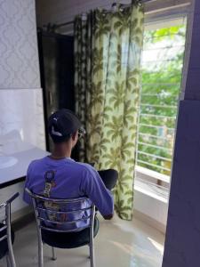 a young boy sitting in a chair looking out a window at Top Comfort in Kolkata +4 photos