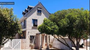 a brick house with a white fence and trees at Visvanger self catering in Britannia Bay