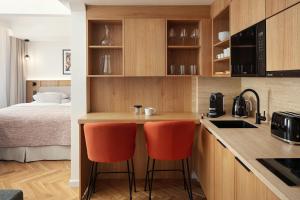 a small kitchen with orange chairs and a bed at Six Residences Prague in Prague
