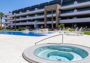 a swimming pool with a hot tub in front of a building at MG Playa Flamenca Village in Orihuela Costa