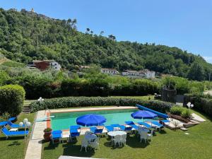 a swimming pool with chairs and blue umbrellas at Villa Volpes con piscina Privata a uso esclusivo tra Versilia e Cinque Terre in Luni