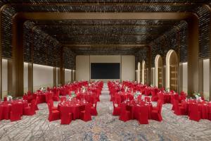a large room with red tables and chairs and a screen at 库尔勒绿发万丽酒店 in Korla +109 photos