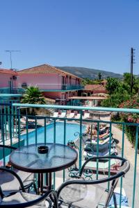 a balcony with tables and chairs next to a swimming pool at Maui Poolside Studios in Laganas