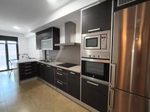 a kitchen with stainless steel appliances and black cabinets at Apartamentos La Aubaga in Valderrobres