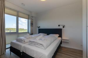a bedroom with a bed with white sheets and a large window at Welcome in - Royaal appartement 'De Zeester' met riant terras I Gorishoeksedijk 41, Scherpenisse in Scherpenisse