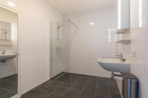 a white bathroom with a sink and a shower at Welcome in - Royaal appartement 'De Zeester' met riant terras I Gorishoeksedijk 41, Scherpenisse in Scherpenisse