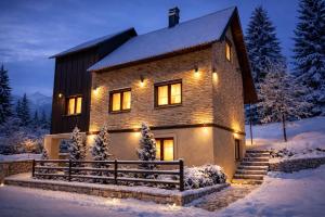 a house with lights on it in the snow at AHAVA Spa Residence in Žabljak