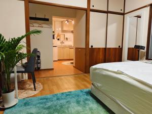 a bedroom with a bed and a table and a bathroom at DiDi Calm 105 in Tokushima