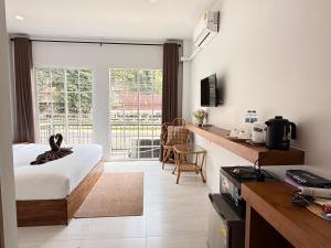 a bedroom with a bed and a kitchen with a window at Chailai room202 in Ban Sai Thai
