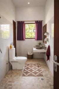 a bathroom with a toilet and a sink and a window at Nuansa Timur Residence in Jimbaran