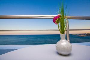 a white vase with a pink flower in it on a table at Astron Hotel in Ierapetra +42 photos