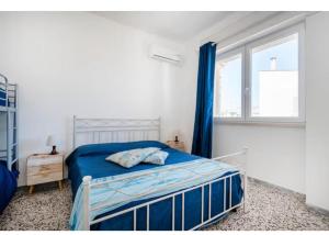a bedroom with a bed with blue sheets and a window at Residenza Marittima in Torre Canne